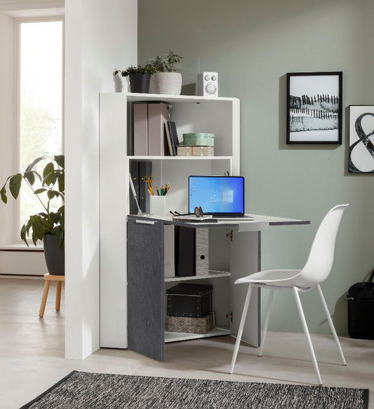A modern White and Report DALIA corner desk with a fold-down door and three shelves, placed in an organized room with a computer set up on the desk, a chair, and decorative items on the shelves. 