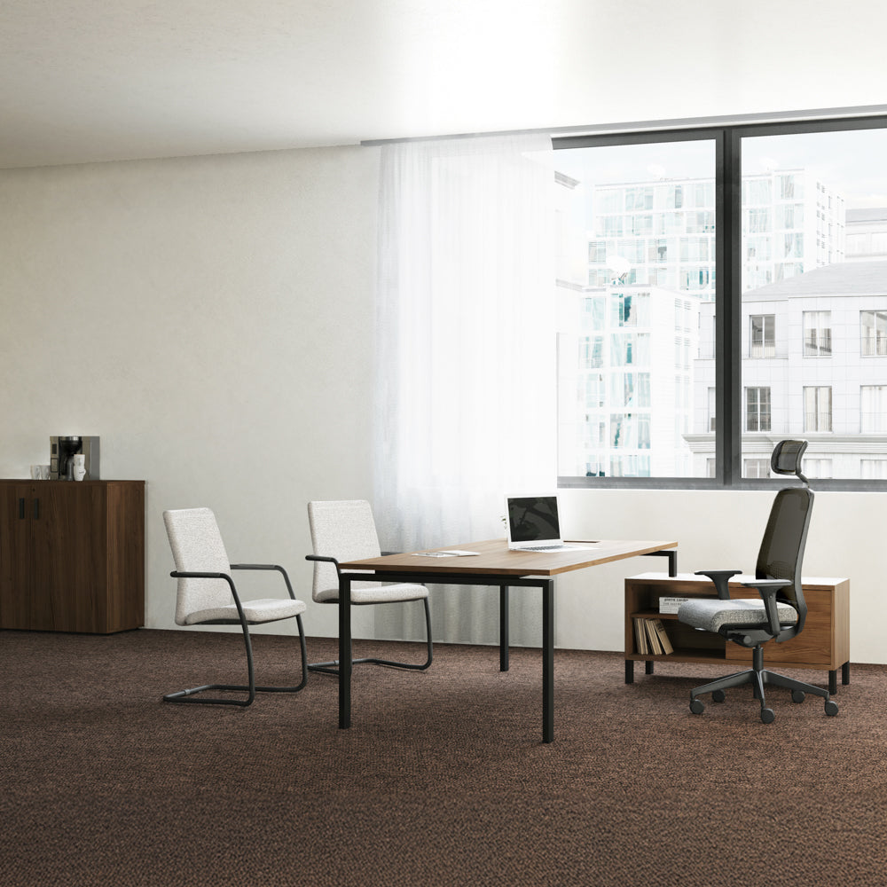 Mise en situation d'un aménagement de bureau moderne et lumineux avec le fauteuil ergonomique Gabin à têtière (assise gris clair), un bureau finition bois et des chaises visiteur.